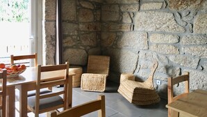 A room with a stone wall, wooden furniture, and a basket of fruit on a table.