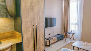 A modern room with a wooden bench, a TV mounted on the wall, a small table, and a chair.