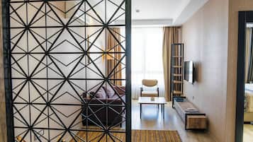 Een hotelkamer met een bank, een bijzettafeltje, een televisie en een houten kast.