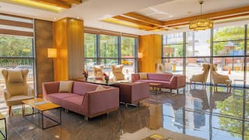 A modern lobby with plush seating, large windows, and a reflective floor.