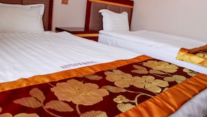 Una habitación de hotel con dos camas individuales, cada una con cabecero y ropa de cama blanca.