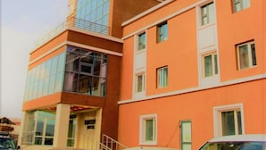 Un edificio de varios pisos con el letrero “KENTAVR HOTEL” en la parte superior. Hay varios coches estacionados adelante y una escalera que lleva a la entrada.
