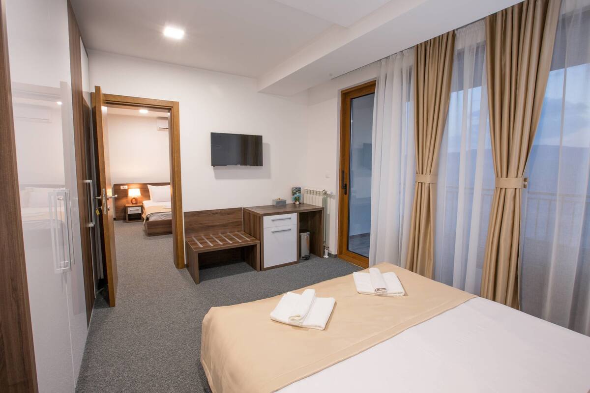 A hotel room with a bed, a desk, a chair, a TV, and a bathroom.