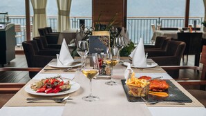 Una mesa de comedor dispuesta con platos de comida, copas de vino y un menú.