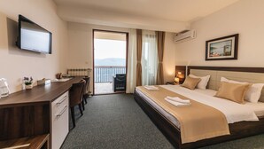 Habitación de hotel con cama, escritorio, silla, televisión y vista al exterior.