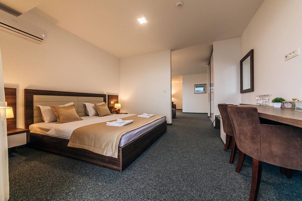 A hotel room with a bed, bedside tables, a desk, and a chair.