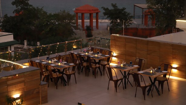 Un espace extérieur aménagé pour les repas, avec des tables et des chaises, un belvédère et une vue sur la plage.