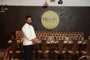 A restaurant interior with a chef standing by a table set for dining.