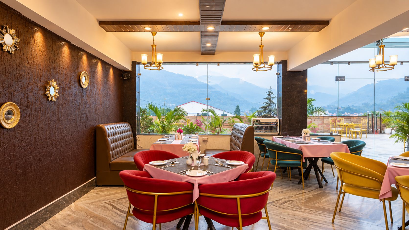 A restaurant with a mountain view, featuring red and yellow chairs, a booth seating area, and a table set with plates and cutlery.
