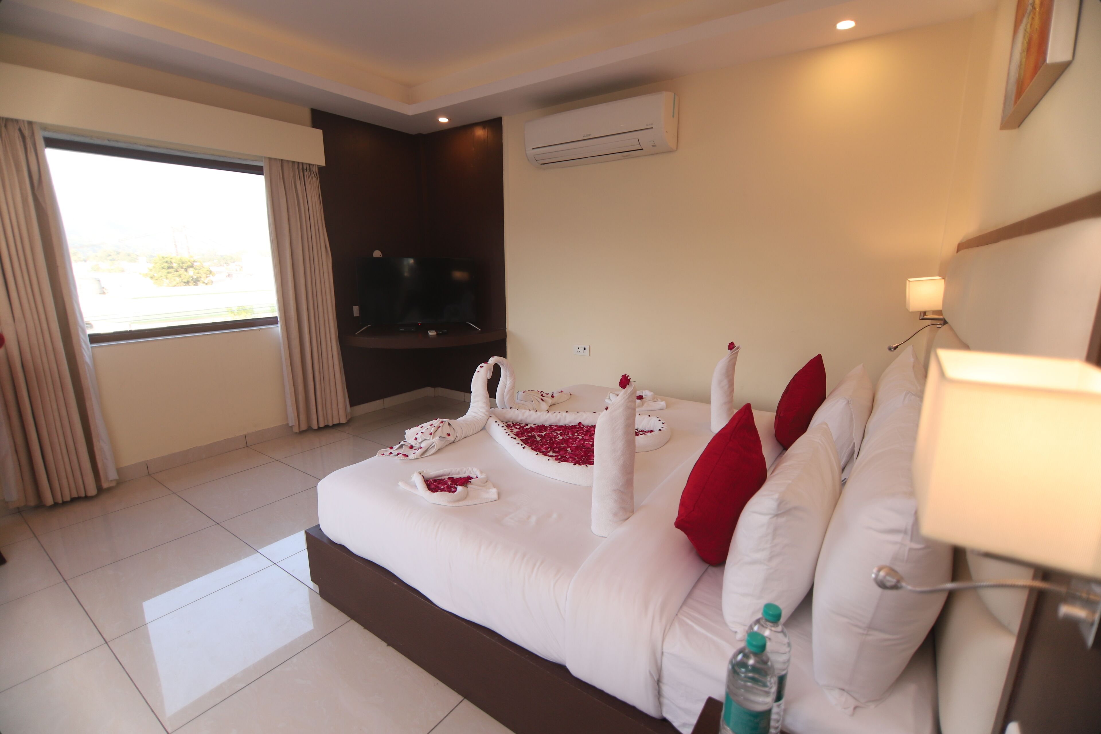 Habitación de hotel con una cama grande, televisión, aire acondicionado y vista al exterior por la ventana.