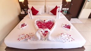 Une chambre d’hôtel avec un grand lit, deux tables de chevet et une tête de lit dotée d’un éclairage intégré.