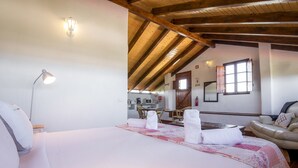 Een slaapkamer met een groot bed, een bureau en een stoel op de achtergrond.