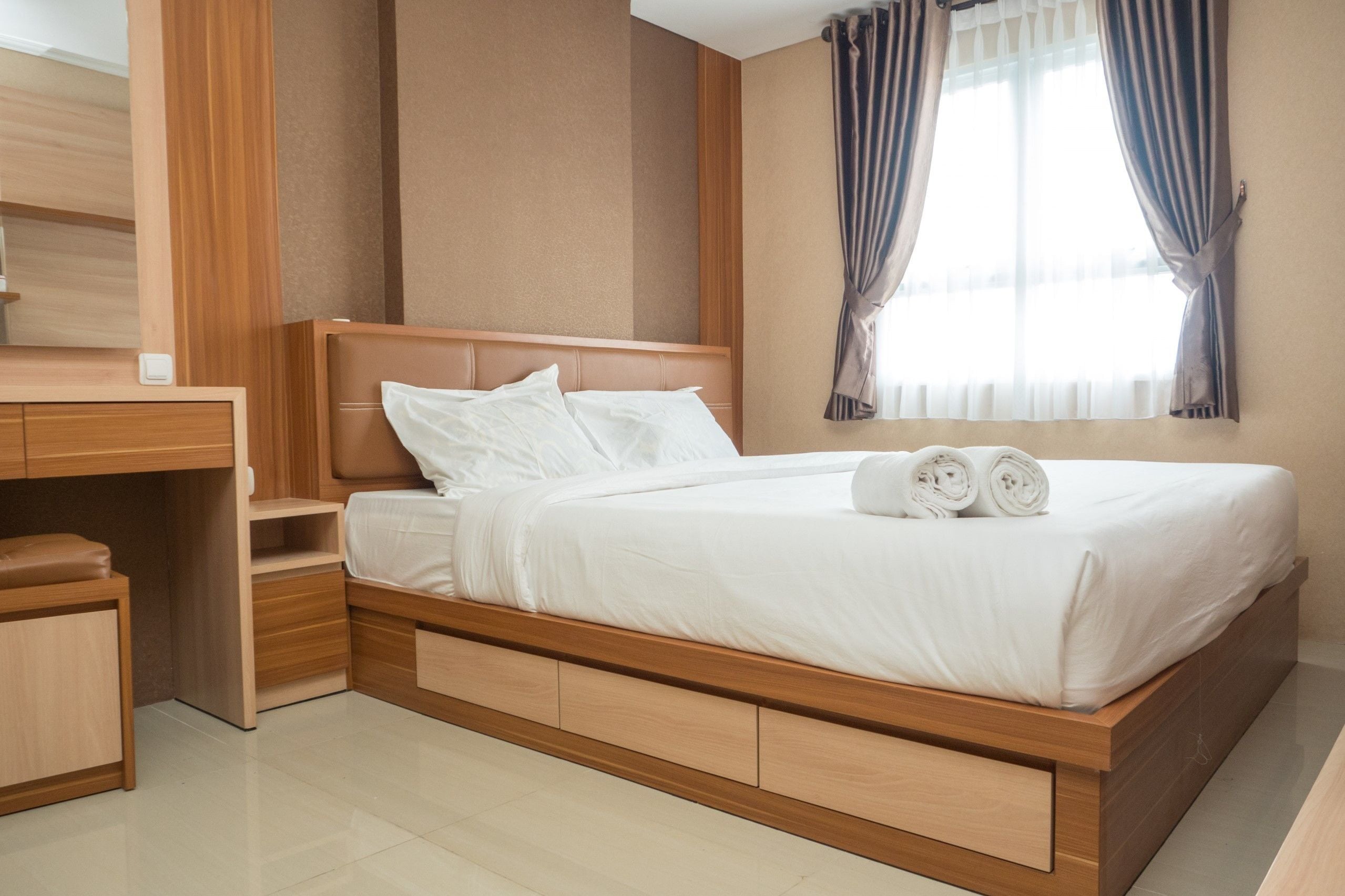 A modern hotel room with a wooden bed, a desk, and a wardrobe.