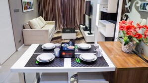 A modern living room with a dining area, a sofa, a TV, and decorative items. - Furnished 1BR City View Casa Grande Apartment (Jakarta)