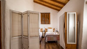 A narrow room with a wooden ceiling, a bed with a checkered bedspread, a wooden wardrobe, and a window with wooden shutters. - F - Casa do Garibaldi in Quinta das Alagoas by DreamAlgarve (Lagos)