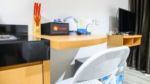 A hotel room with a kitchenette, a travel-themed sign, a kettle, a TV, and a chair. - Cozy Studio Room Bintaro Icon Apartment (South Tangerang)