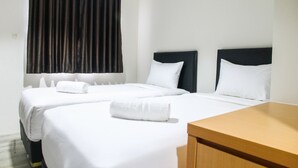 A hotel room with two beds, white bedding, a wooden nightstand, and a large window with dark curtains. - Cozy Studio Room Bintaro Icon Apartment (South Tangerang)
