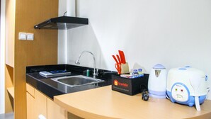 A compact kitchen with a black countertop, stainless steel sink, and a travel coffee maker. - Cozy Studio Room Bintaro Icon Apartment (South Tangerang)
