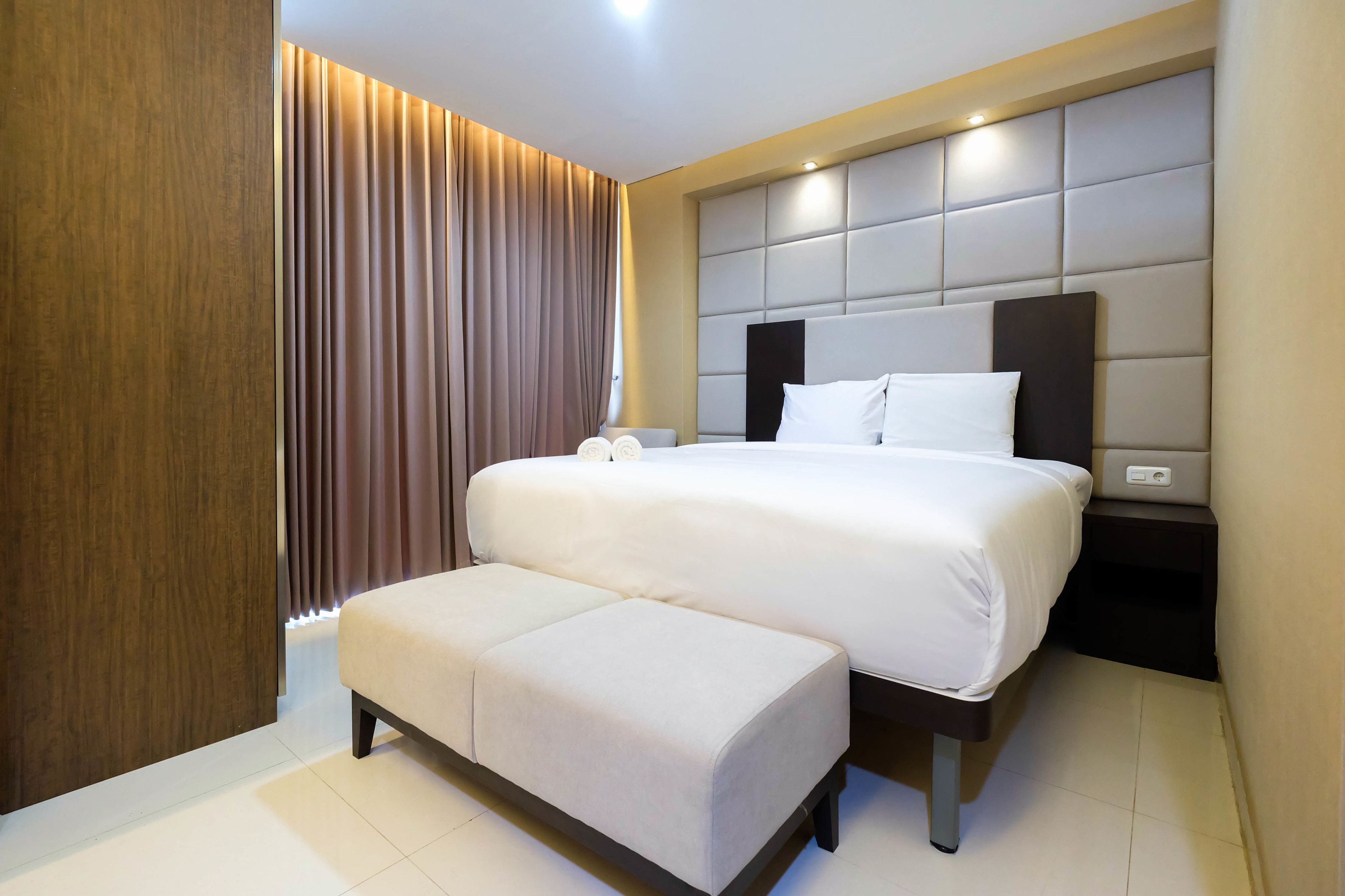 Una habitación de hotel moderna con una cama grande, una mesita de noche y un banco empotrado.