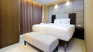 A modern hotel room with a large bed, a bedside table, and a built-in bench. - Minimalist Style Studio Brooklyn Apartment near IKEA Alam Sutera (South Tangerang)