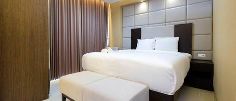 Una habitación de hotel moderna con una cama grande, una mesita de noche y un banco empotrado.