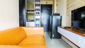 A compact living space with a sofa, a kitchenette, and a TV. - Cozy and Elegant 1BR Apartment Belmont Residence (Jakarta)