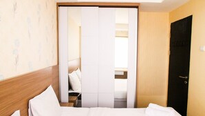 A hotel room with a bed, a wooden headboard, a wardrobe, and a door. - Cozy and Elegant 1BR Apartment Belmont Residence (Jakarta)