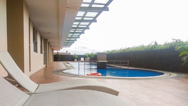An outdoor swimming pool area with lounge chairs and a pergola overhead. - Cozy and Elegant 1BR Apartment Belmont Residence (Jakarta)