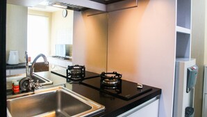 A kitchen with a stainless steel sink, a gas stove, and a built-in oven. - Cozy and Elegant 1BR Apartment Belmont Residence (Jakarta)
