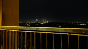 A nighttime cityscape viewed from a balcony with a metal railing. - Strategic Studio The Oasis Cikarang near Omni Hospital (Cikarang)