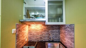A compact kitchen with a built-in stove, a stainless steel sink, and a stone backsplash. - Strategic Studio The Oasis Cikarang near Omni Hospital (Cikarang)