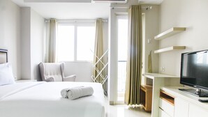 A hotel room with a bed, a chair, a TV, and a window with curtains.