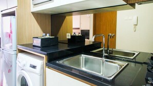 A compact kitchen with a microwave, a washing machine, and a double sink.