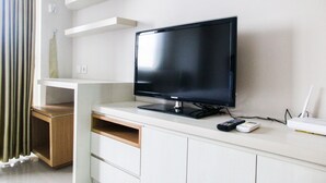 A modern living room with a flat-screen TV on a white entertainment unit, a wooden cabinet, and a white router.