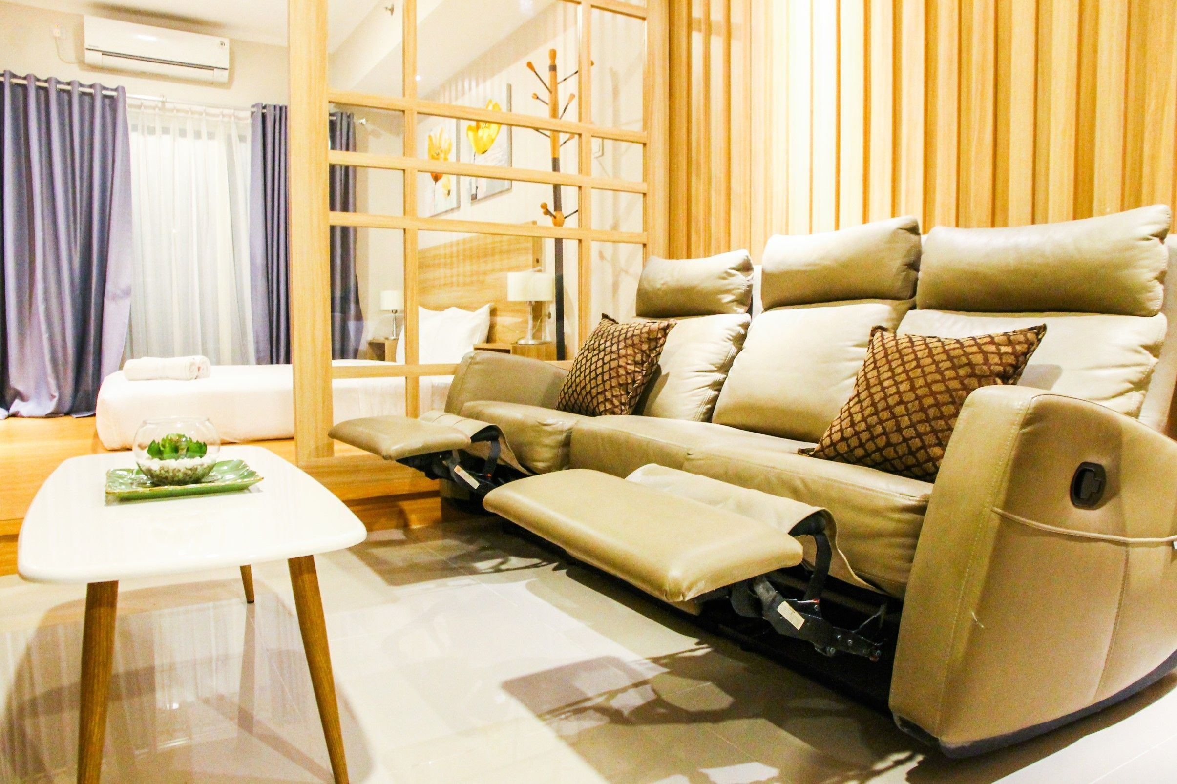 A modern living room with a beige sofa, a glass coffee table, and a small side table.