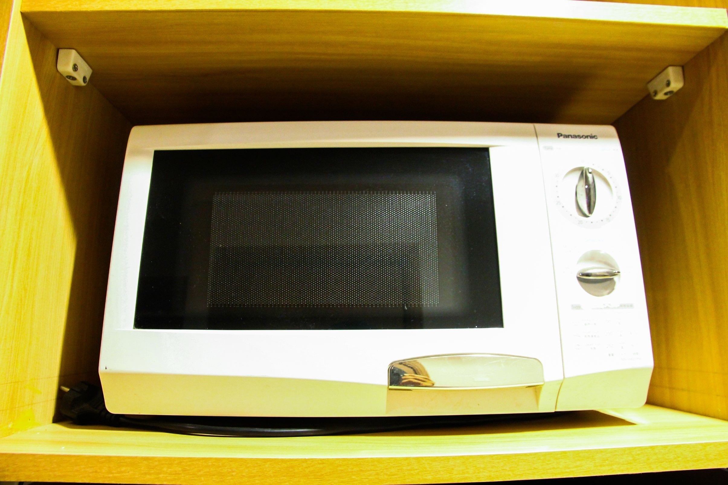 Un horno microondas Panasonic blanco dentro de un mueble de madera.