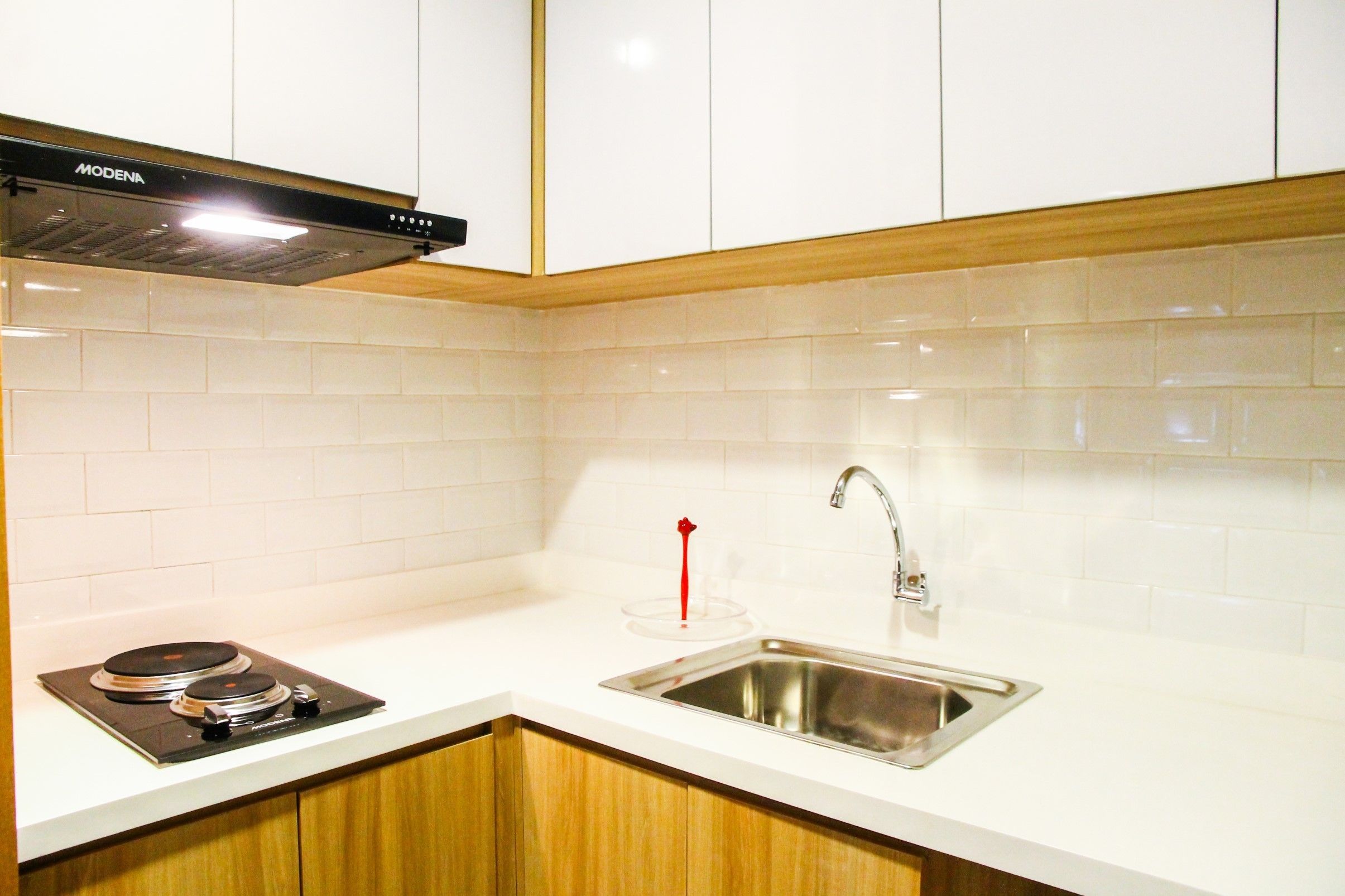 A kitchen with white cabinets, a stainless steel sink, and a black stove.