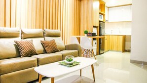 Un salon moderne avec un canapé, une table basse et un coin cuisine à l’arrière-plan.