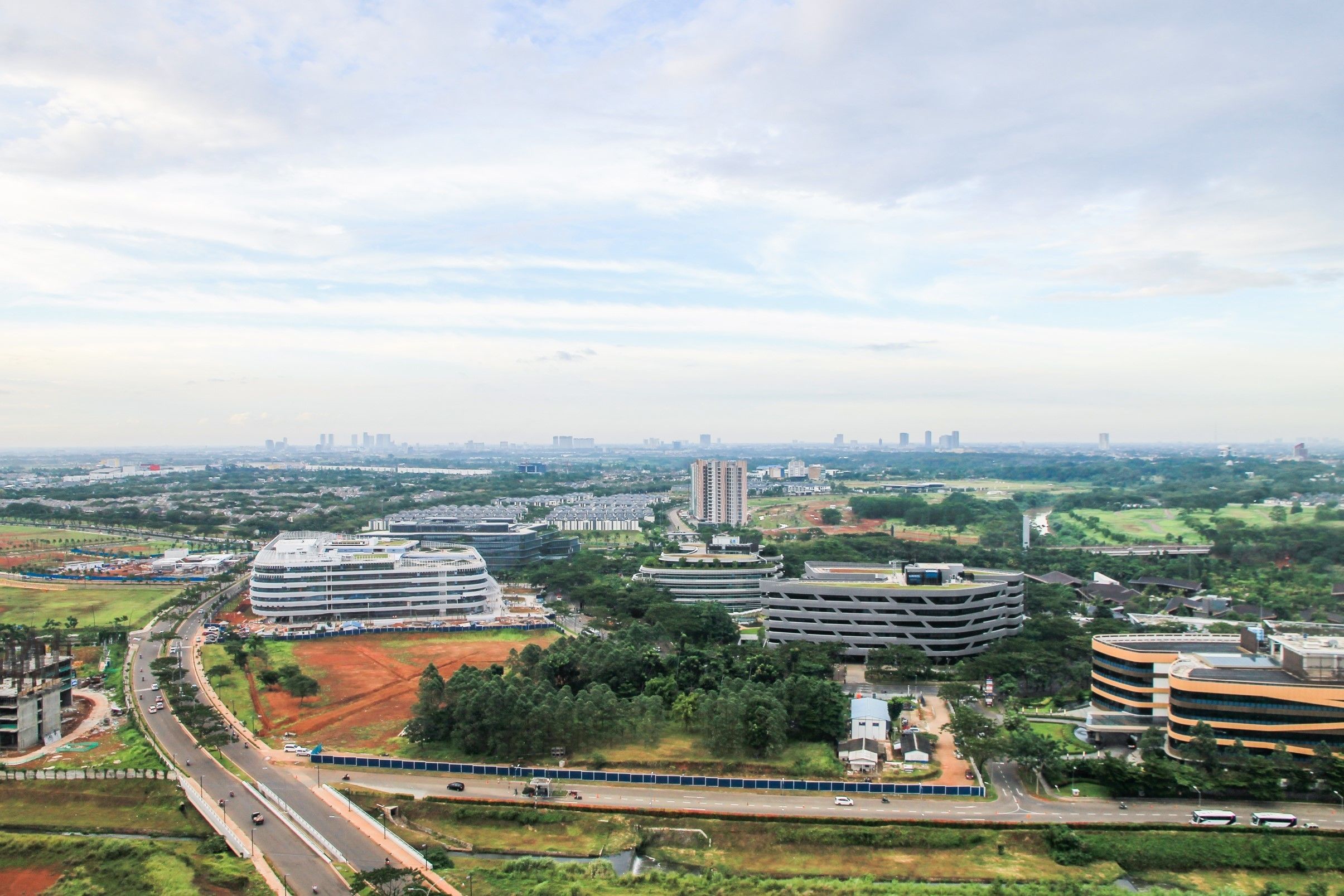 Un paisaje urbano moderno con una combinación de edificios comerciales y residenciales, una autopista y zonas verdes.