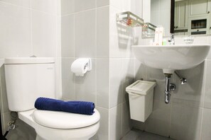 Une salle de bain équipée de toilettes, d’un lavabo et d’un porte-rouleau de papier toilette.