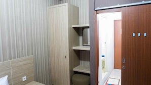 A room with a wardrobe, a small stool, and a door leading to another area.