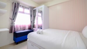 Ein Schlafzimmer mit einem Bett, einer blauen Bank, einem Kleiderschrank und einem Fenster mit Vorhängen.