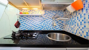 Eine Küche mit schwarzem Arbeitsplatz, einer Spüle aus Edelstahl und blau-weißen Mosaikfliesen.