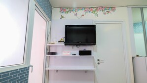 Ein Badezimmer mit einer weißen Tür, einem an einer Ablage montierten Fernseher und einer Blumensticker an der Wand.