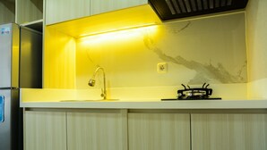 A kitchen with a built-in stove, a sink, and a stainless steel refrigerator. - Sophisticated Studio at The Oasis Apartment (Cikarang)