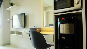 A modern hotel room with a flat-screen TV, a water dispenser, and a minimalist design. - Sophisticated Studio at The Oasis Apartment (Cikarang)