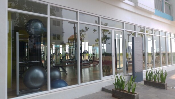 Une salle de sport dont on peut apercevoir les équipements d’entraînement à travers de grandes fenêtres.