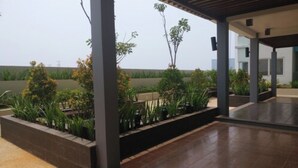Un espace extérieur couvert, aménagé en patio, avec des jardinières et un plancher en bois.