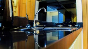 Une cuisine dotée d’un évier en acier inoxydable, de meubles en bois et d’un plan de travail noir.