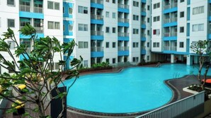 Un immeuble moderne à plusieurs étages, doté d’une piscine centrale entourée de balcons.